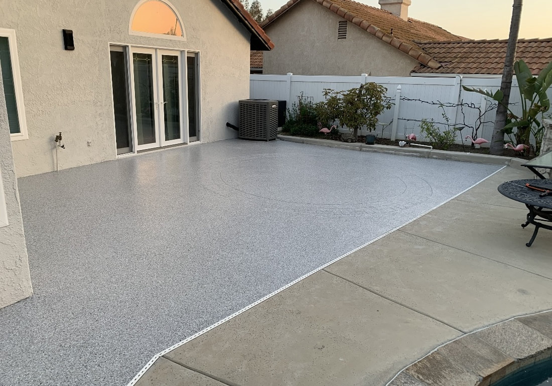 Backyard patio coated in a gray epoxy flake finish